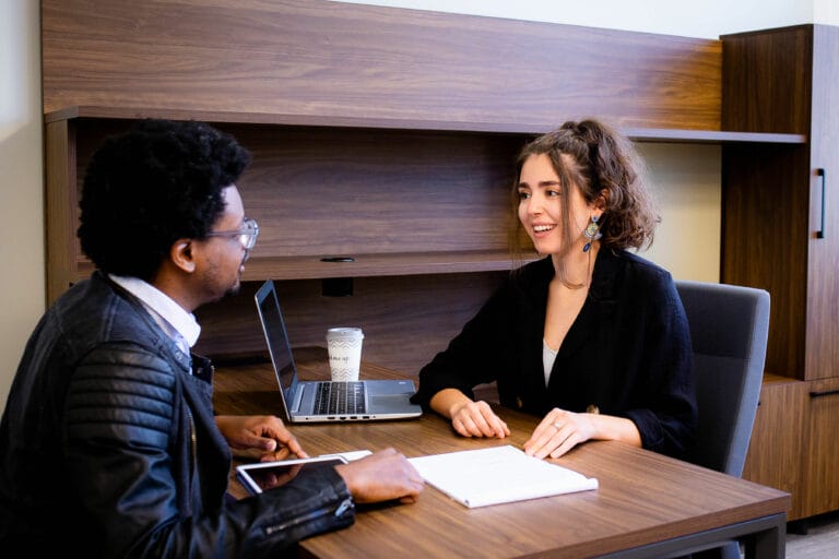 Business professional man and woman meeting in an office discussing papers.